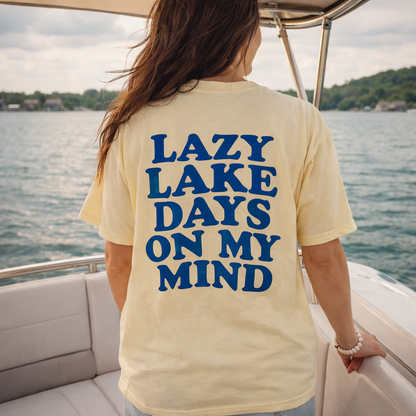 Yellow short sleeve t-shirt with bold blue text reading ‘Lazy Lake Days on My Mind’ on the back.